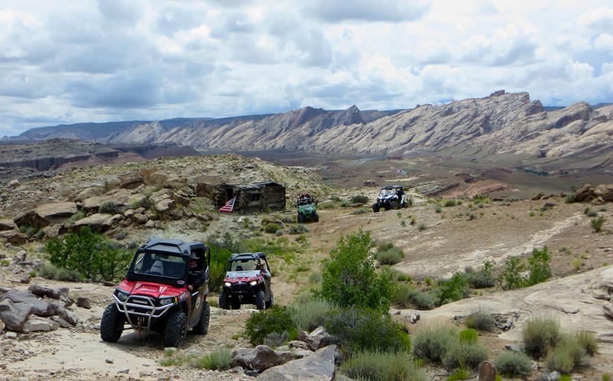 Four OHV's drive past a historical building outside the San Rafael Swell. 