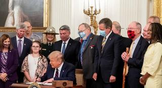 Twenty one people including the President and Vice President line for the photo opportunity behind the desk as the Great American Outdoors Act is signed