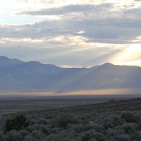 Sun peeking through the clouds as it shines across a mountain range in the Utah. 