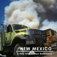 A New Mexico Pecos District Fire Truck in front of a plume of smoke.