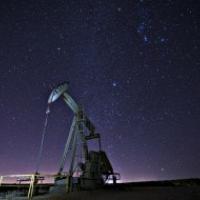 A pump jack against a starry night sky.