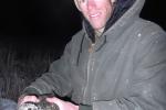 Man wearing a head lamp and holding a sage-grouse fitted with a radio collar. 