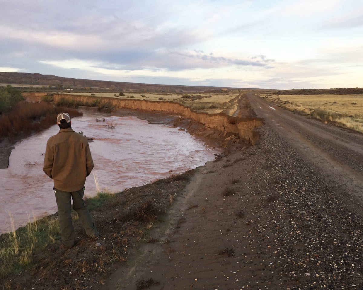 Man stands next to swollen river.