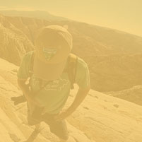 A person standing on a rock cliff examining their phone