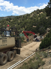 Blue Sky with Red Backhoe Performing Reclamation