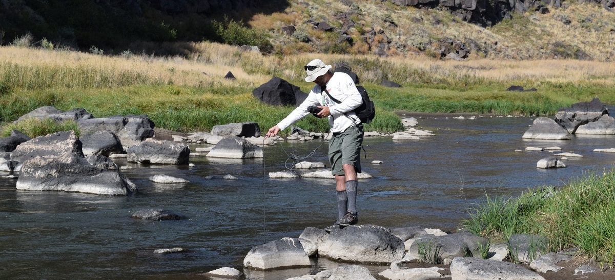 Biologist lowering a thermometer into the Rio Bonito within the FT. Stanton National Conservation Area