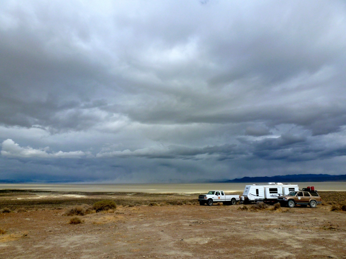 A camper sits in a green field under a gray sky.