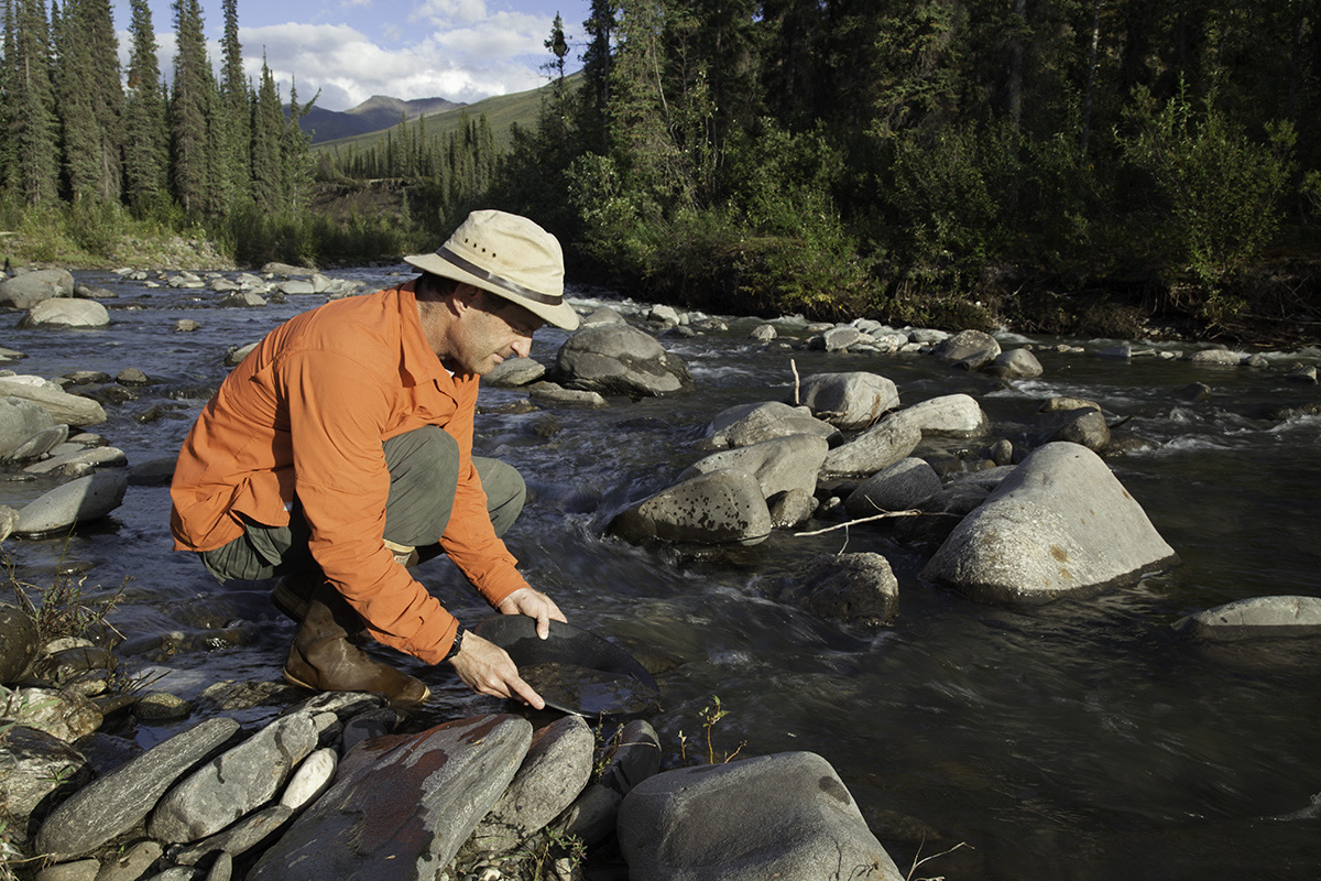 man gold panning in a stream along the Dalton Highway in Alaska