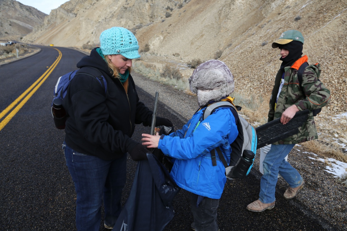 Cub Scout Den leader (on the left) assists two Cub Scouts with pieces of tire collected during the service project.