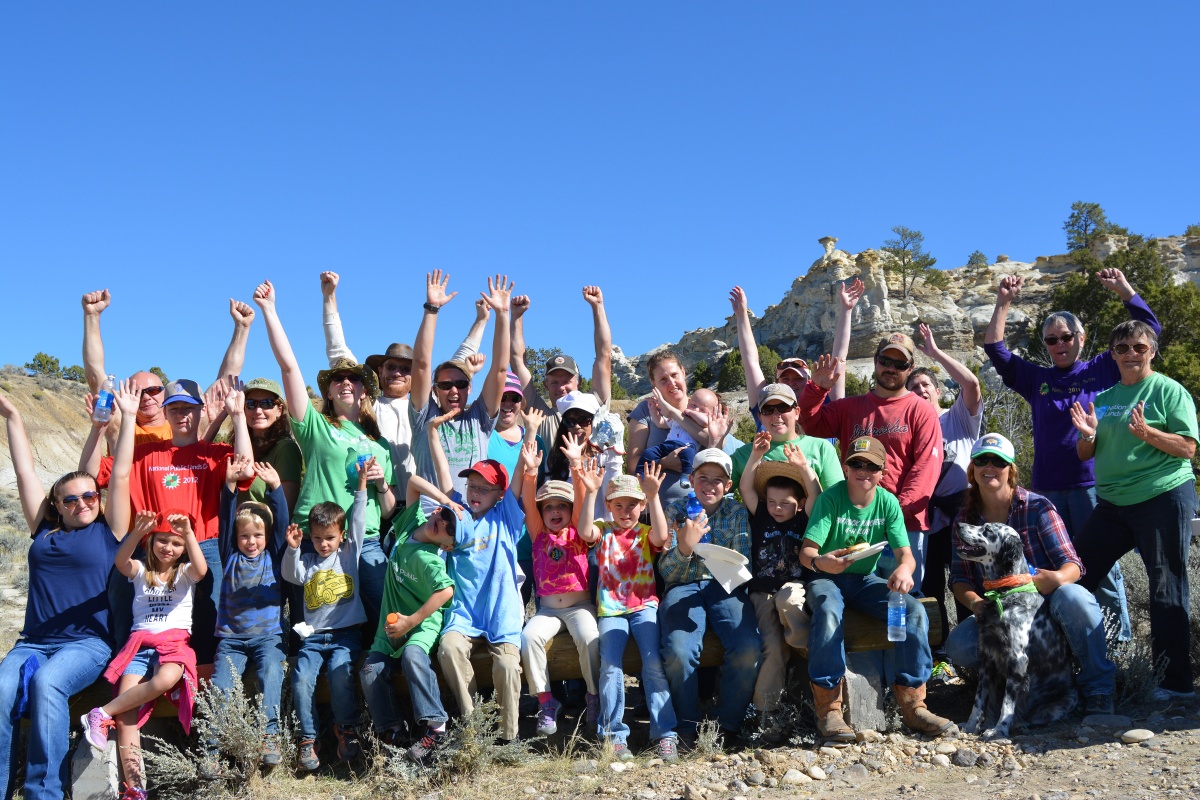 Group of 30 volunteers raise their hands in the air.