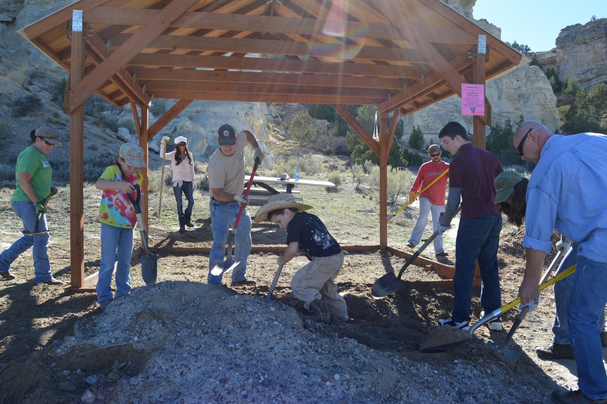 group of adults and children use shovels digging in a picnic shelter