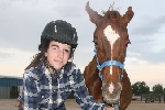 Teenager stands with a mustang in a halter. BLM photo