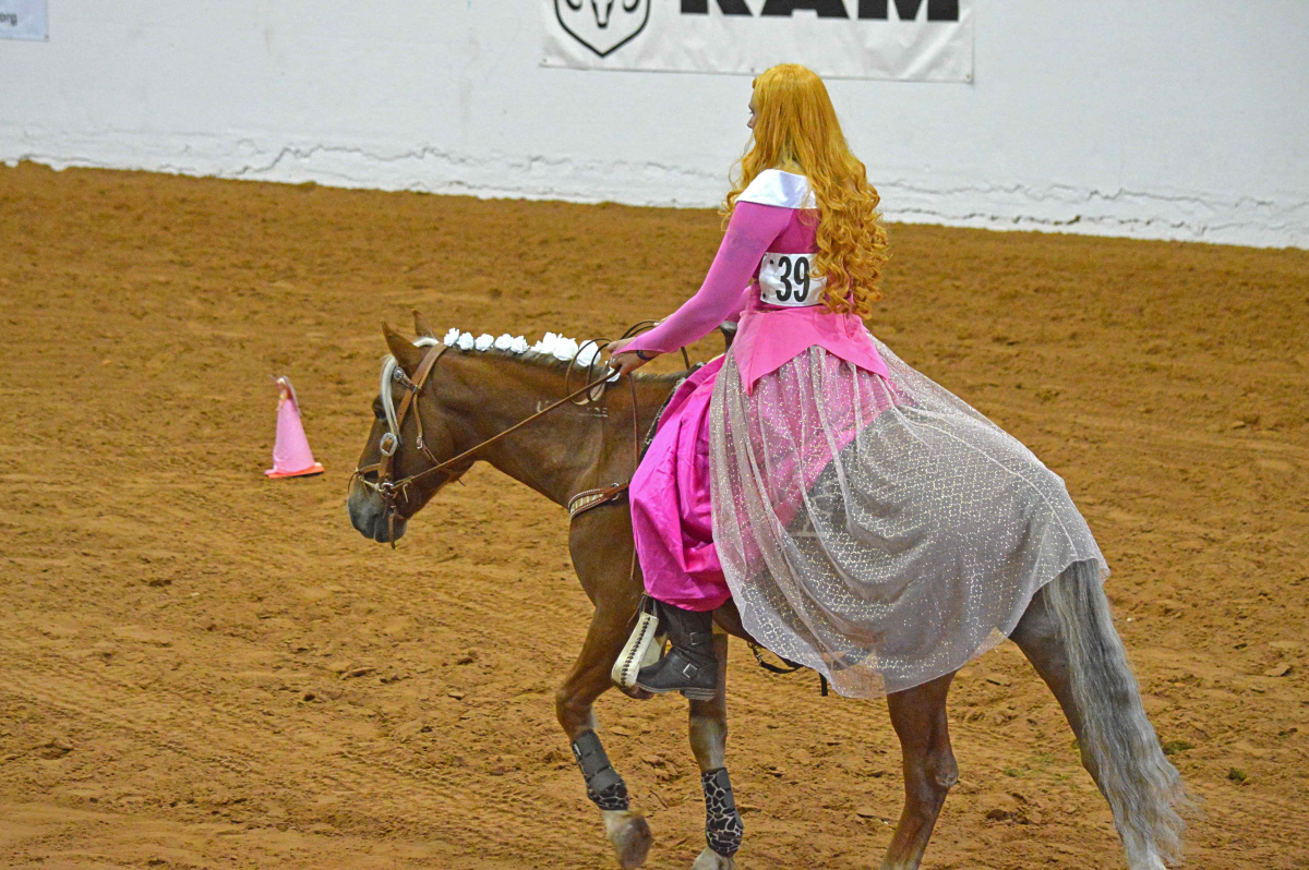 Woman in costume on horse in an arena. 