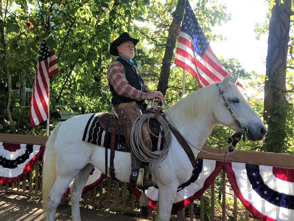 A man on a horse with the American flag behind him. 