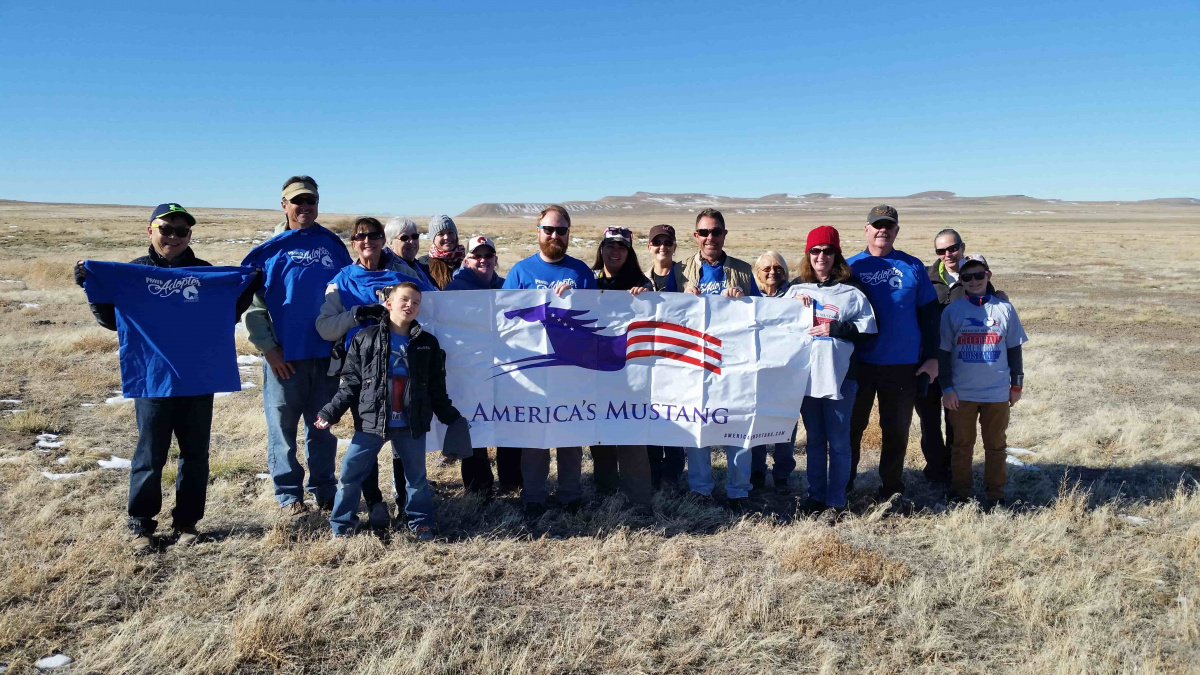 A groups of volunteers standing on the range with a banner. 