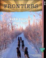Cover of Frontiers issue 124 "Fall in Love with Your Trails" featuring a dog sled team on a trail in the White Mountains National Recreation area with the light hitting the frosty trees making them look pink