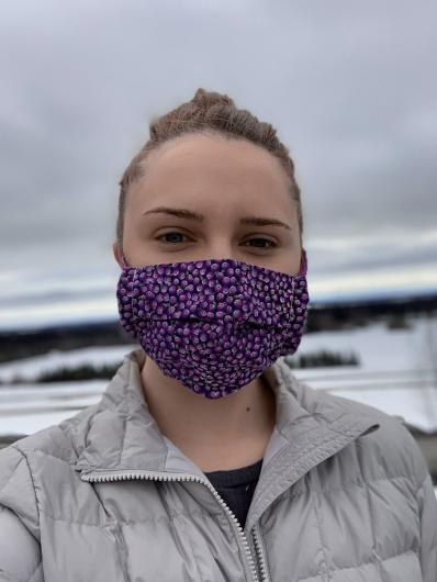 A young woman wearing a purple face mask.