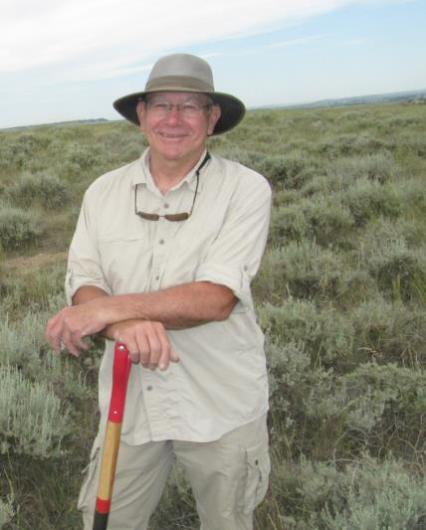 Bill Volk in the field posed leaning on a shovel.