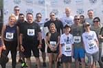 BLM Law Enforcement and their family members wearing running apparel standing in front of a background with logos for the Police Week 5K and the sponsors of the event.