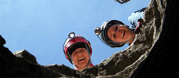 Two BLM staff wearing hard hats looking down into a large mining shaft