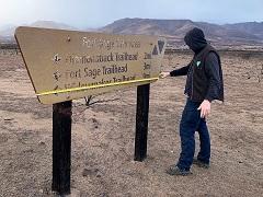 A man measures a burnt sign at Ft  Sage. Photo by the BLM.
