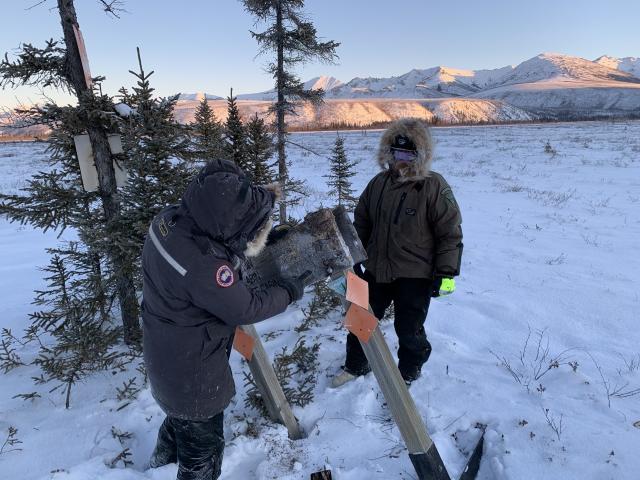 Two men working on sign in snow