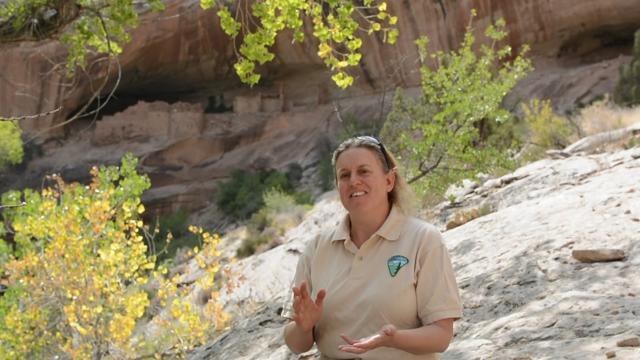A women in a BLM shirt speaking in front of a brush covered landscape in Bears Ears National Monument.