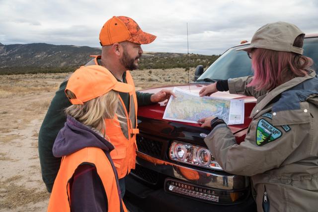 A BLM employee providing directions to hunters using a map on the hood of a truck in John Wesley Powell National Conservation Area managed by the Vernal Field Office. Photo by Bob Wick.