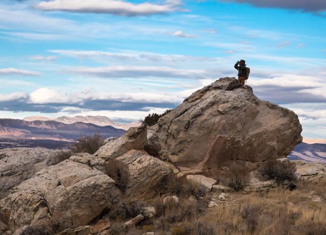 A hiker using binoculars while exploring John Wesley Powell National Conservation Area managed by the Vernal Field Office