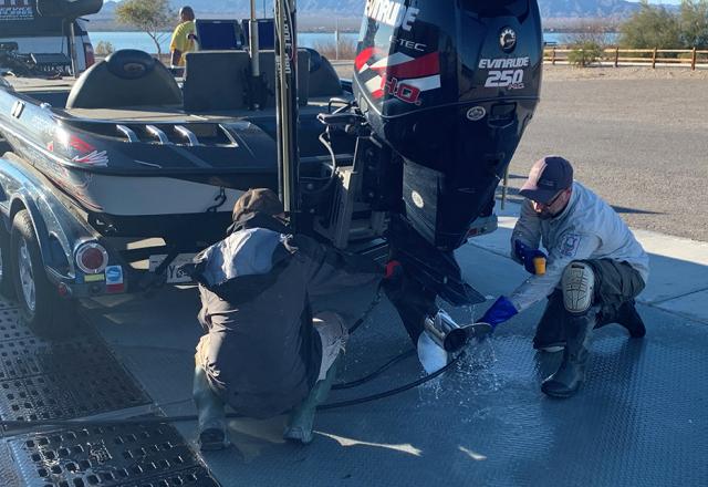 people clean a boat's motor