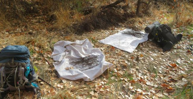 rolls of barbed wire on the ground with tarps and backpacks