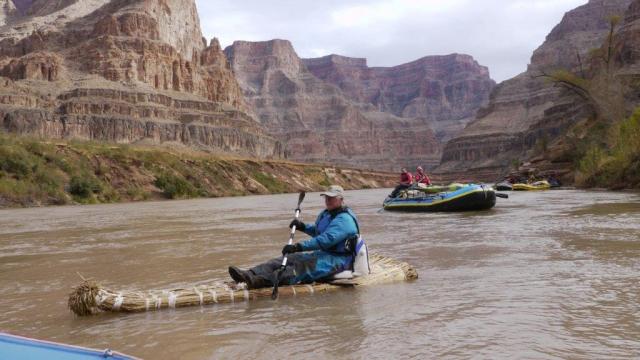 a man with a kayak paddle rides the tule raft in the river
