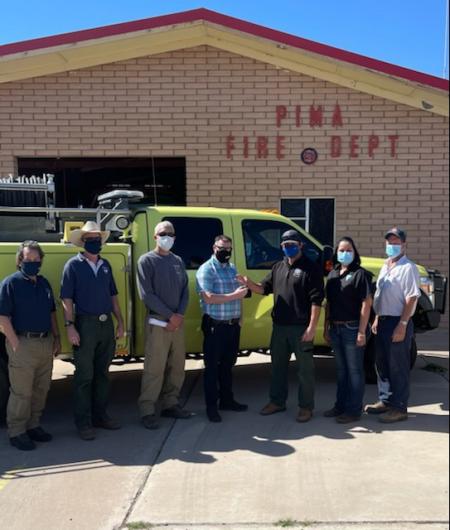 Members of the Gila District, AZ DFFM and Pima Fire Department standing in front of a fire engine in front of the Pima Fire Department.