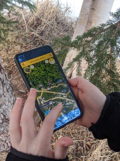 A hand holding a cell phone with the Agents of Discovery app open on it