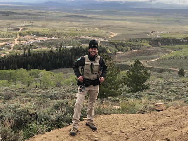 Uniformed BLM law enforcement ranger stands on vista