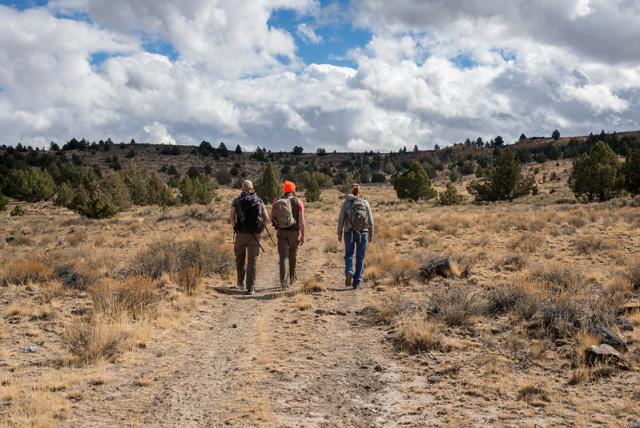 Three visitors hike along a trail through the sagebrush