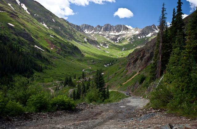 Green mountain landscape with snow-capped peaks and blue sky in the background