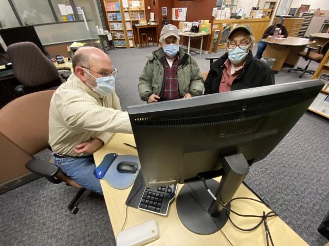 Three men looking at a computer screen