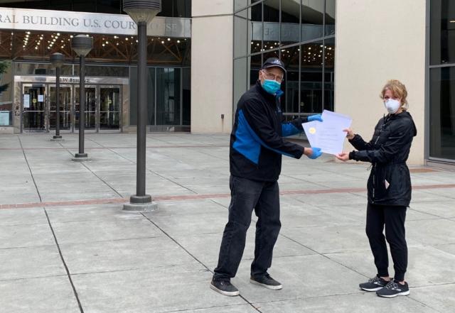 A man and woman hold final land patents outside the Anchorage Federal Building. 