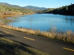 a paved bicycle path next to a wooded lake. BLM Photo