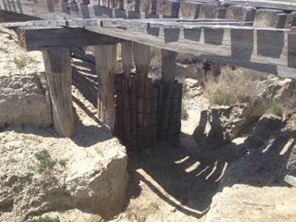 This photo depicts the trestle during the implementation of the stabilization project. The pressure treated posts are attached to the original piers.