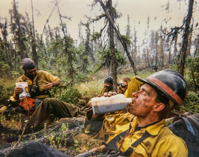 Then Chena Hotshot John Lyons takes a swig of cold, instant coffee on a break from fighting the Miller’s Reach fire in 1996. Photographer unknown.