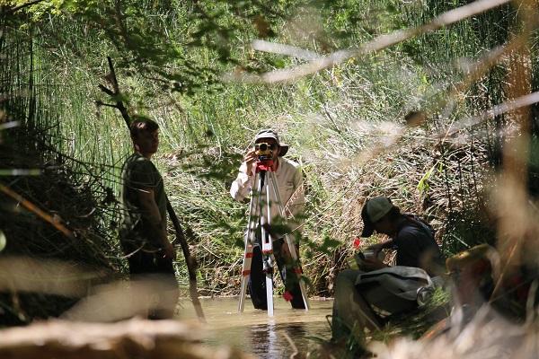 Crewmembers use stadia rod and auto level to measure slope of the stream reach. 