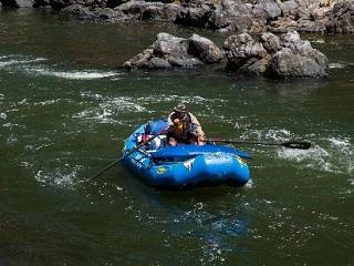 photo showing a person floating a craft on a river