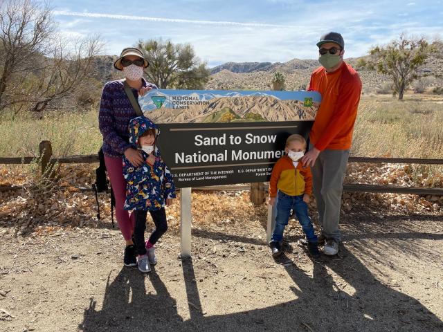 Family stands next to a monument sign.