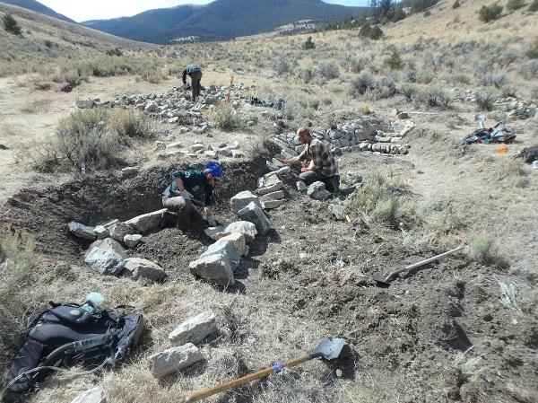 Workers assembling a rock structure with a mountain in the background.