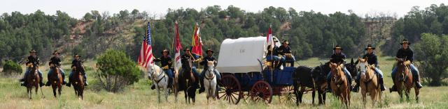 Cavalry on horseback and a covered wagon. 