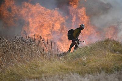 firefighter tending a prescribed burn in a meadow
