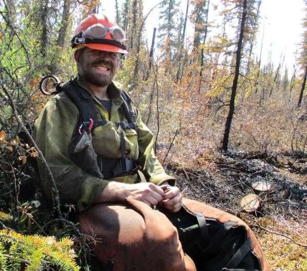 Smiling firefighter sitting on the tundra map in a forest.