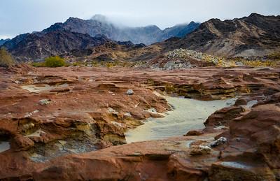 Red sandstone foreground with black mountains in the background